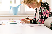 Eine junge Frau schreibt etwas mit farbigen Stiften auf eine Metaplanwand.